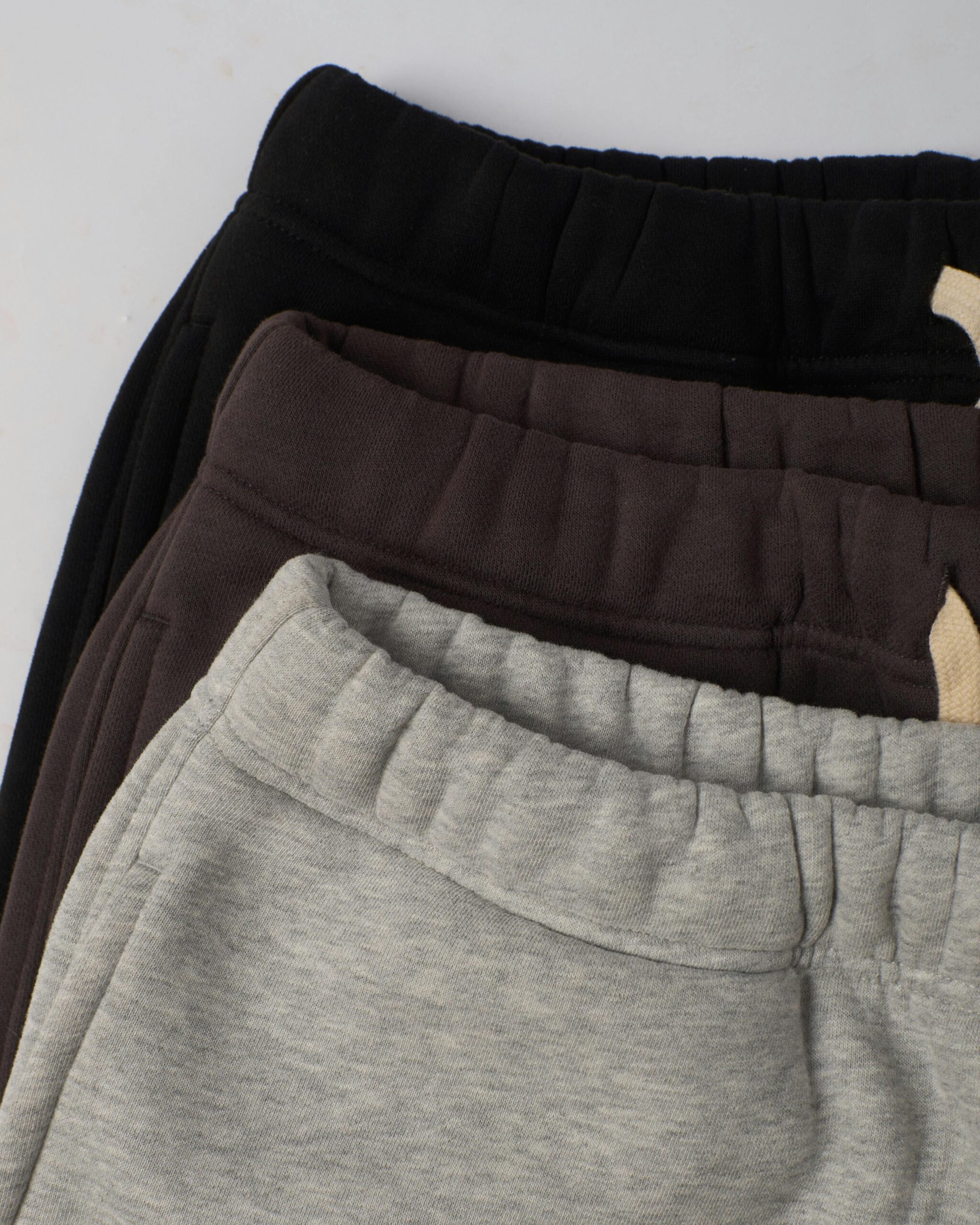Top view of folded sweatpants in black, brown, and gray tones, ideal for casual fashion.
